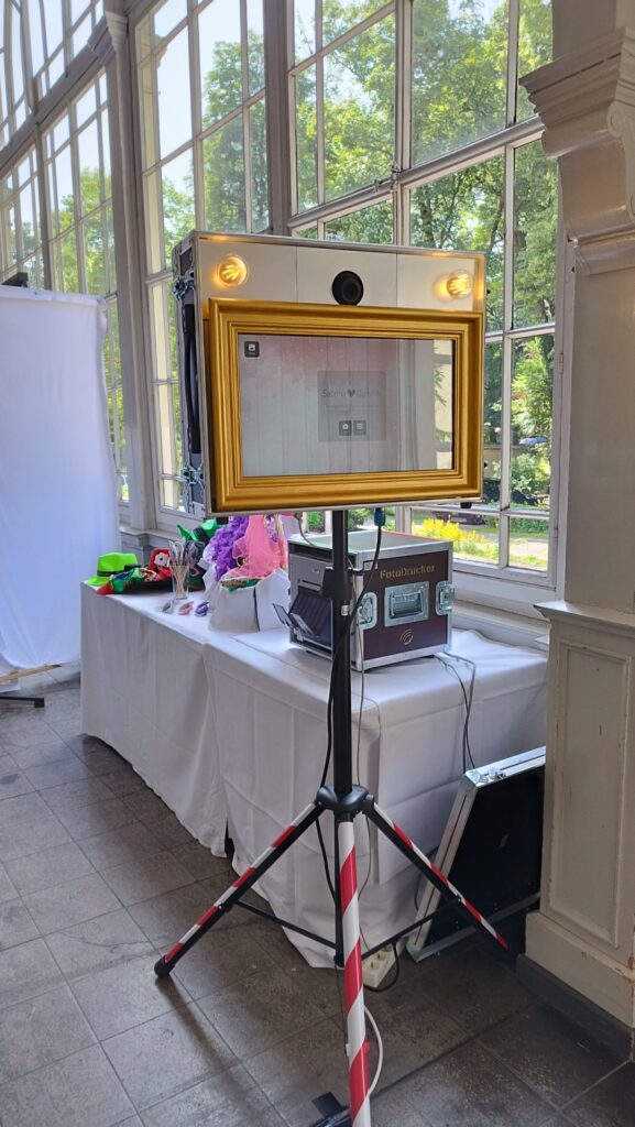FotoBox auf Stativ mit FotoDrucker und Accessoires im Hintergrund